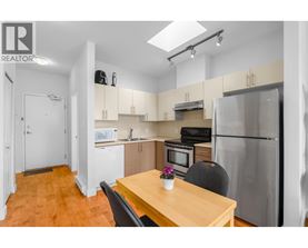 A kitchen with a table and chairs in the foreground and a refrigerator in the background.