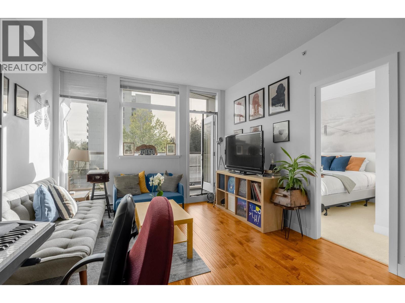 A living room with a piano, a couch, a chair, a TV, and a plant.