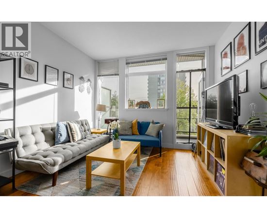 A living room with a grey couch, a wooden coffee table, and a television on a wooden stand.