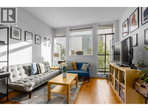 A living room with a grey couch, a wooden coffee table, and a television on a wooden stand.