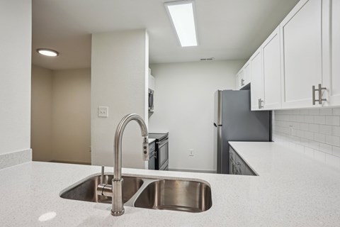 A kitchen with a sink and a refrigerator.