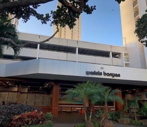 A building with a sign that reads "walhi banyan" in front of it.