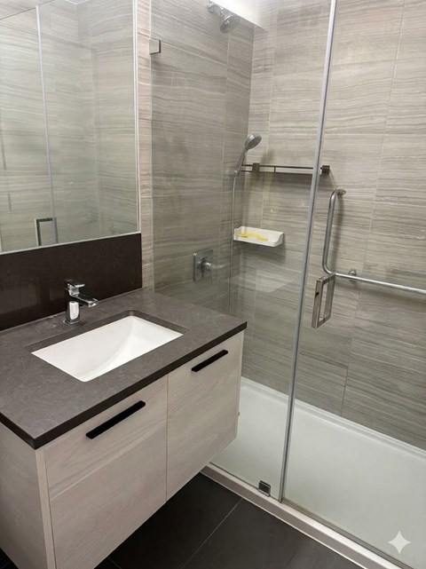 A bathroom with a sink and a glass shower stall.