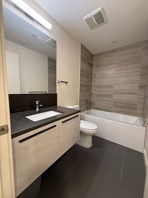 A modern bathroom with a sink, toilet, and bathtub.