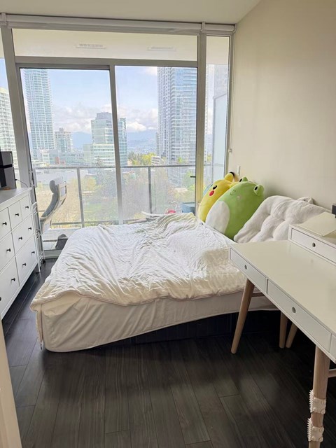A bedroom with a large bed and a balcony overlooking the city.