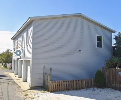 A small white building with a wooden fence in front.