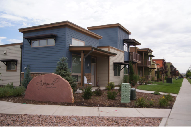 A house with a blue exterior and a brown rock in front of it.