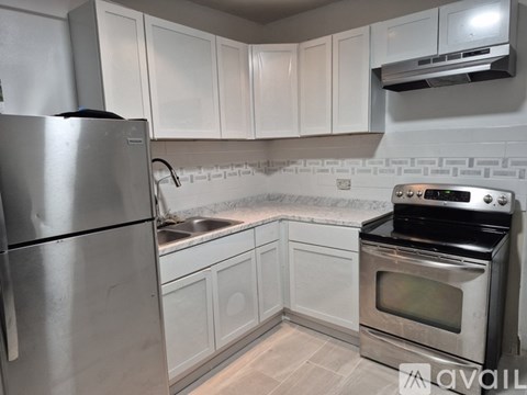 A kitchen with white cabinets and a stainless steel refrigerator.