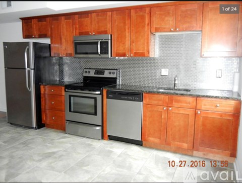 A kitchen with wooden cabinets and a black refrigerator.