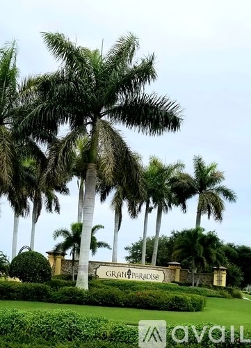 A sign that says Grand Paradiso is in front of some palm trees.