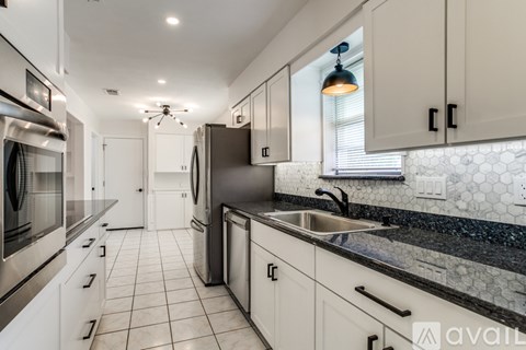 A modern kitchen with white cabinets and black countertops.