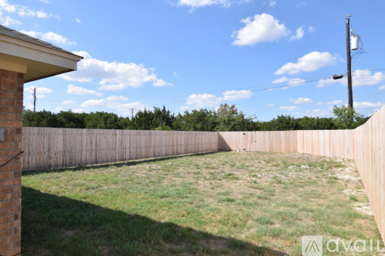 A backyard with a wooden fence and a grassy area.