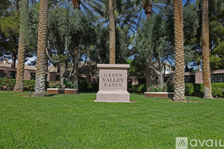 A sign in front of palm trees that says Green Valley Ranch.