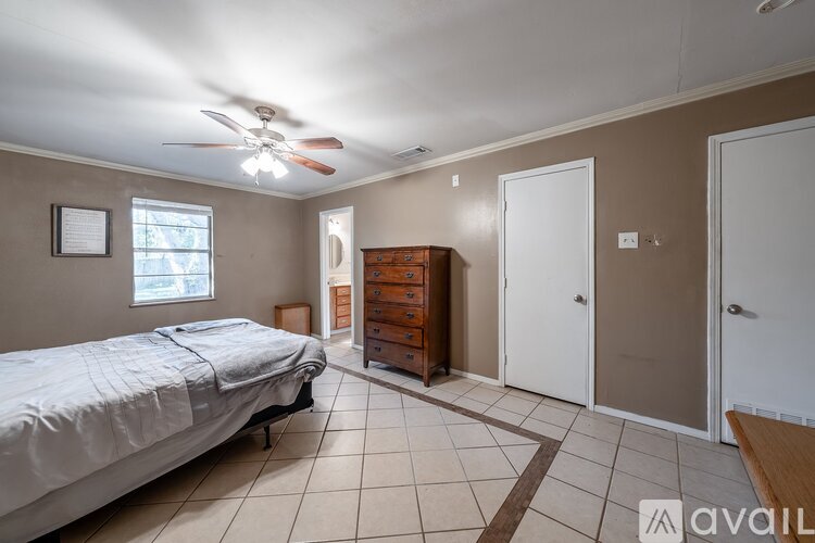 A bedroom with a bed, dresser, and a ceiling fan.
