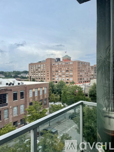 A view from a balcony overlooking a cityscape with buildings and trees.