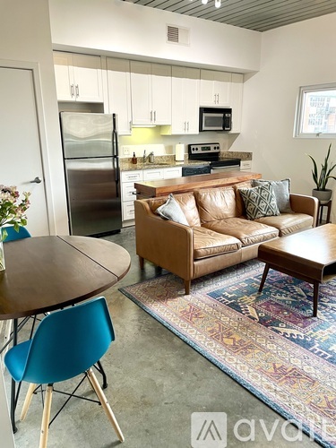 A kitchen with a refrigerator, microwave, and oven is visible through the cabinets.