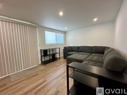 A living room with a grey couch and a wooden floor.