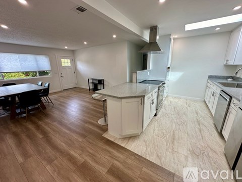 A kitchen with a wooden floor and white cabinets is available for rent.
