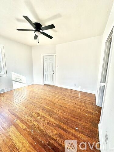 A room with a ceiling fan and wooden flooring.