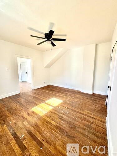 A room with wooden flooring and a ceiling fan.