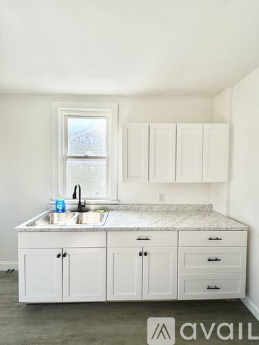 A kitchen with white cabinets and a marble countertop.