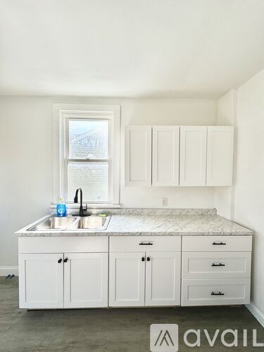A kitchen with white cabinets and a marble countertop.