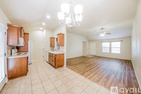 A well-lit kitchen with wooden cabinets and a chandelier.