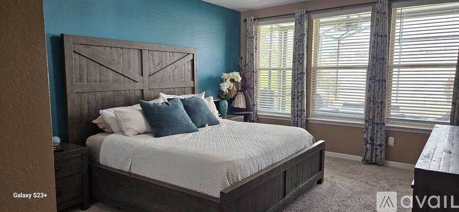 A bedroom with a large bed and a window with blinds.