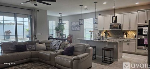 A modern living room with a large sectional sofa and a kitchen area in the background.
