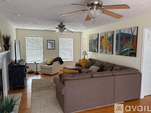 A living room with a brown couch, a fireplace, and a painting on the wall.
