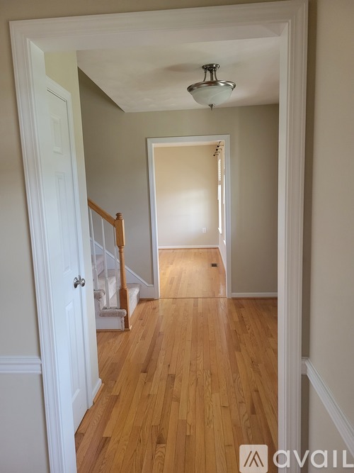 A hallway with wooden floors and white walls.