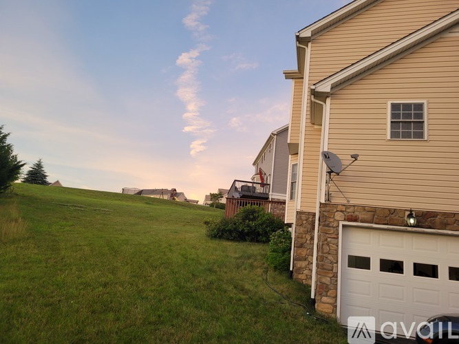 A house with a garage is situated in a grassy area.