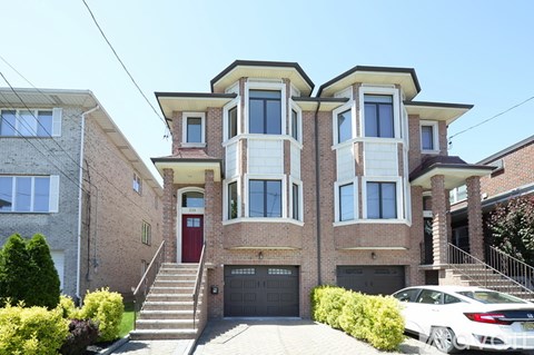 A white car is parked in front of a two-story house.