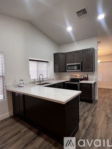 A kitchen with dark brown cabinets and a white countertop.