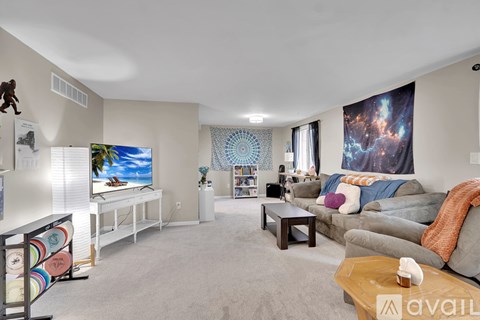 A living room with a grey couch and a wall hanging of a galaxy.