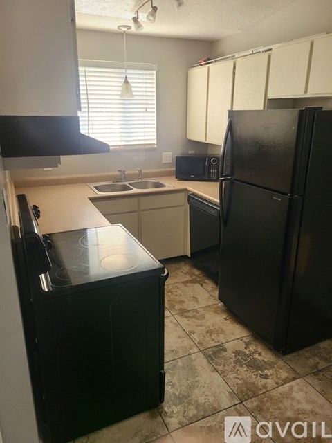 A black refrigerator sits in a kitchen with a black dishwasher and a black microwave.