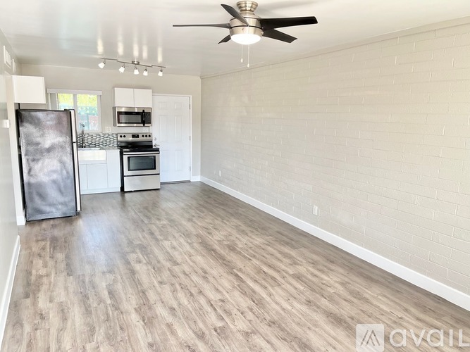 A spacious room with a ceiling fan and wooden flooring.