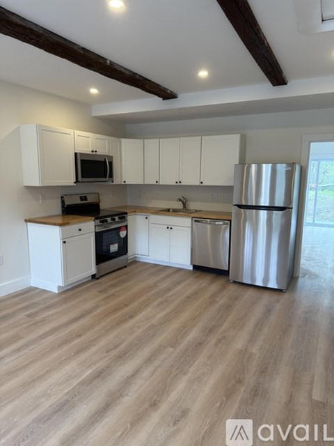 A kitchen with white cabinets and a wooden floor.