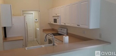 A kitchen with white cabinets and a white refrigerator.