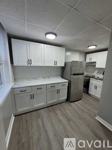 A kitchen with white cabinets and a stainless steel refrigerator.
