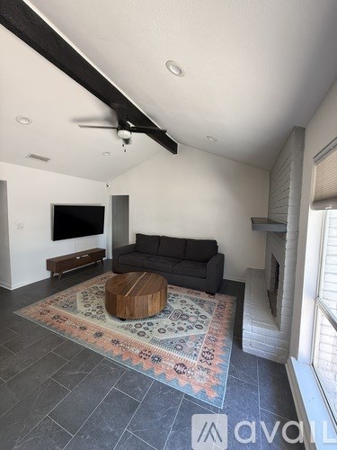 A living room with a black couch and a wooden coffee table.