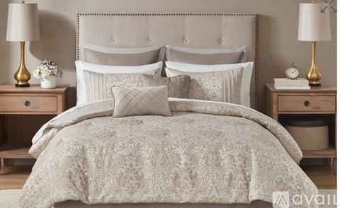 A bed with a patterned comforter and matching pillows is flanked by two lamps on wooden nightstands.