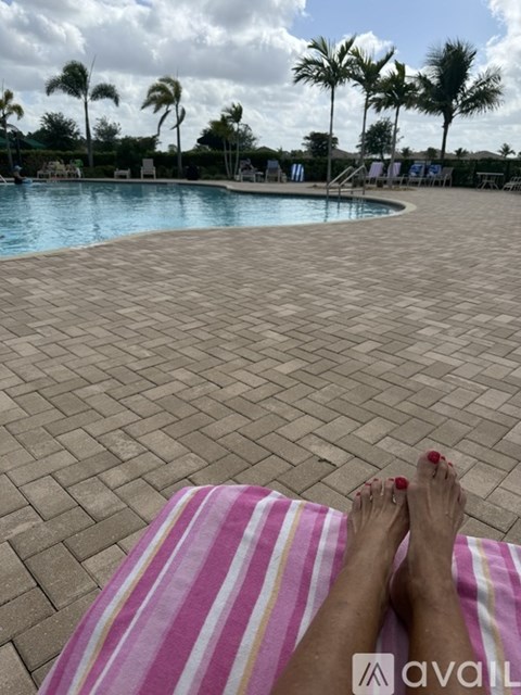A person is sunbathing on a striped towel by a pool.