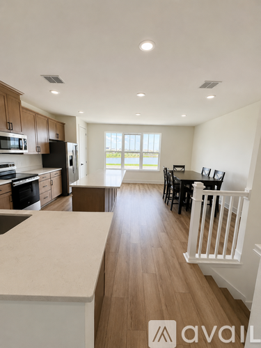 A spacious kitchen with wooden floors and white countertops.
