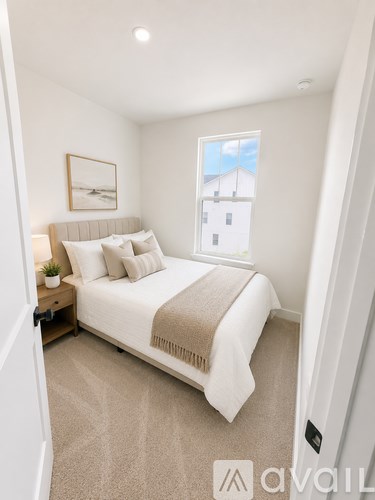 A bedroom with a large bed and a window showing a house.