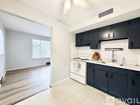 A kitchen with black cabinets and a white stove top oven.