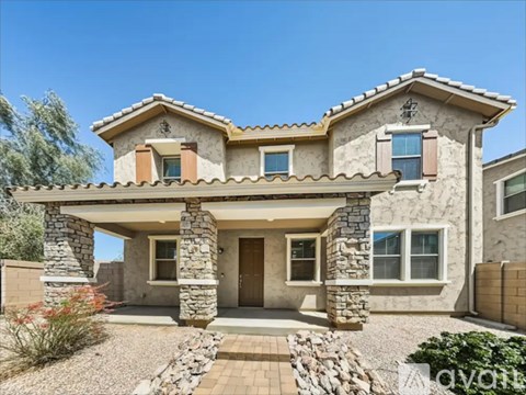 A modern house with a stone facade and a covered entrance.