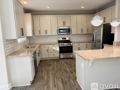 A kitchen with white cabinets and a wooden floor.
