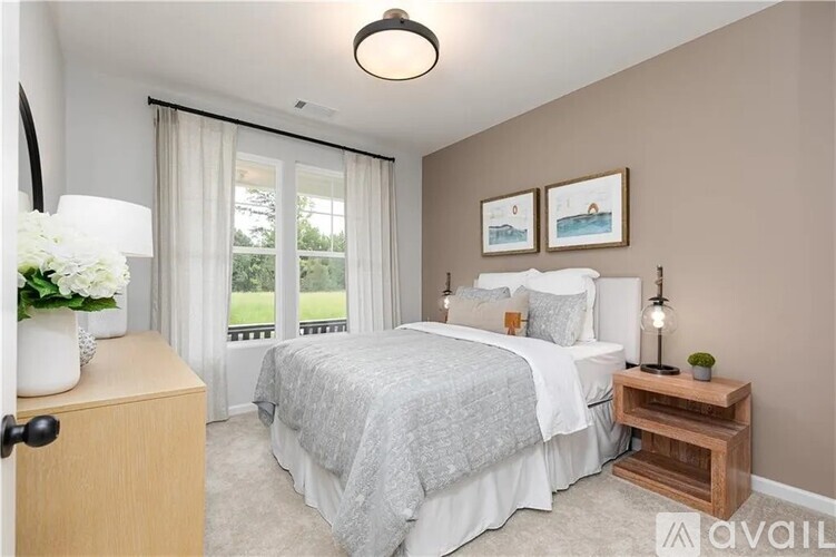 A bedroom with a large bed and a window with curtains.