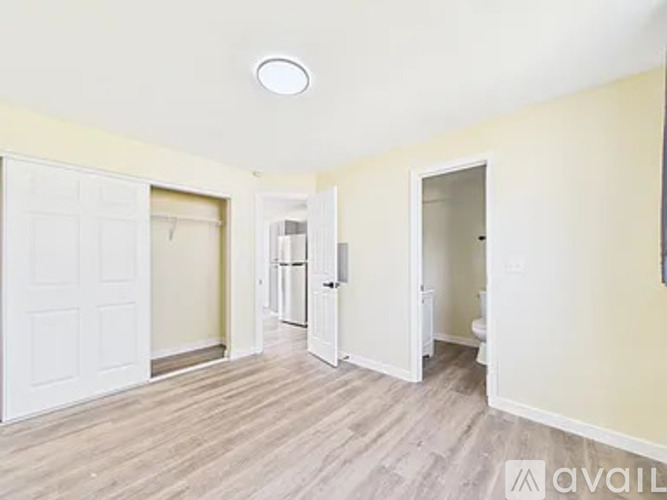A spacious room with a door on the left and a toilet in the corner.